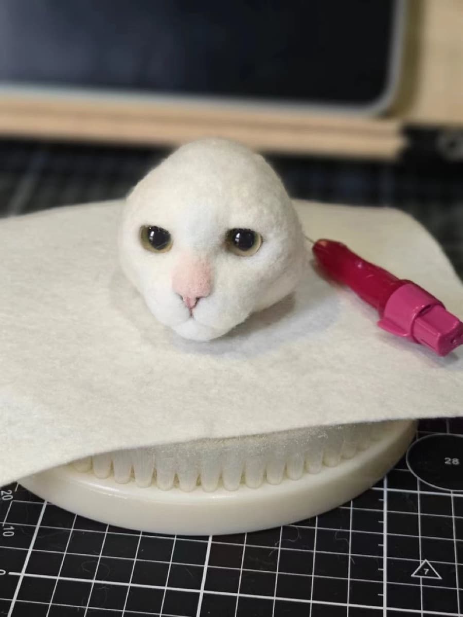 White cat head with felting needle